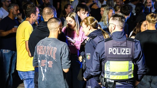 Zwei Polizeibeamte sprechen mit Besuchern der Party.