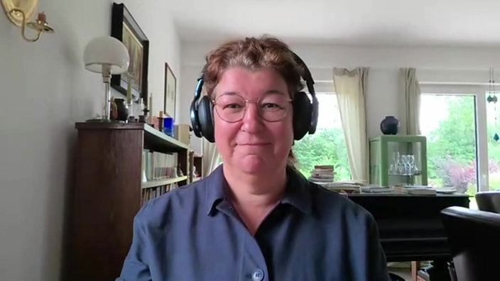 Kriminologin Christine Morgenstern sitzt mit einem Headset am Schreibtisch.
