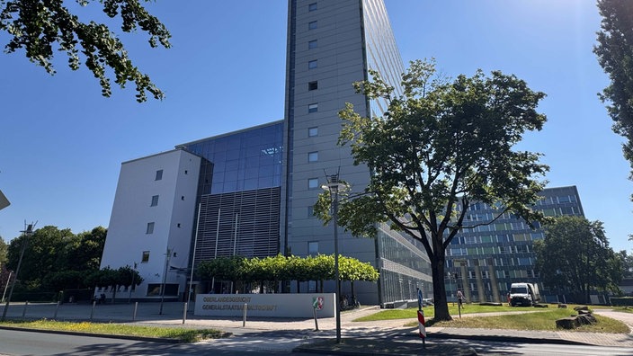 Ein halb graues und halb verglastes modernes Gebäude, davor ein Schild mit der Aufschrift "Oberlandesgericht Generalstaatsanwaltschaft".