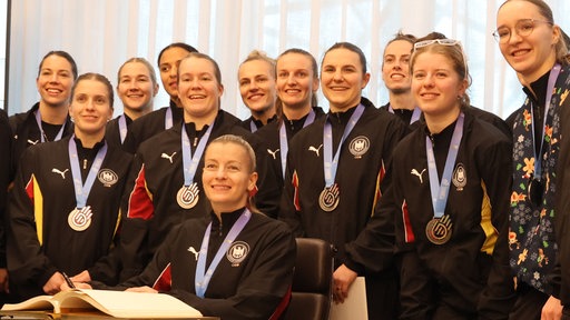 Die Handballnationalmannschaft der Frauen steht um einen Schreibtisch in Dortmund. Dort tragen sie sich ins Goldene Buch der Stadt ein.