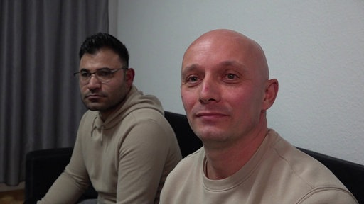 Alin Crasta und Mohammad Alisso sitzen nebeneinander auf einer Couch