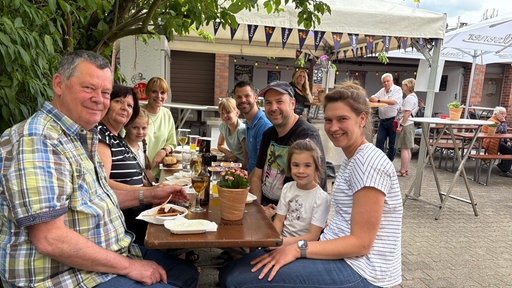 Gäste sitzen mit Essen und Trinken in einem Hinterhof