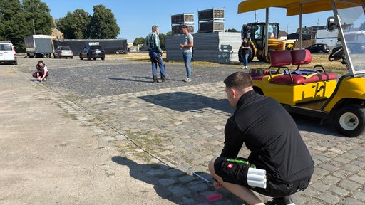 Eine Fläche auf dem Kirmesplatz wird mit dem Maßband ausgemessen.