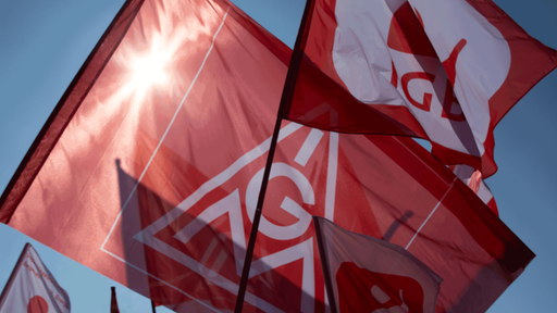 Flaggen mit Symbol der IG Metall schwenken vor blauem Himmel