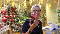 Eine Frau mit einer Weihnachtskugel in einem Dekoladen