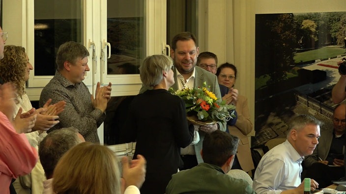 Thorsten Schranz bekommt einen Blumenstrauß überreicht, um ihn herum stehen Leute und klatschen