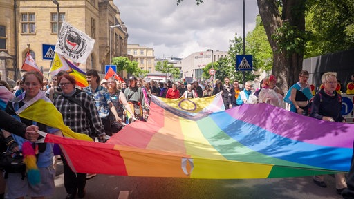 Mehrere Menschen beim Christopher Street Day in Recklinghausen tragen eine riesige Regenbogenfahne.