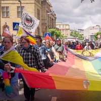 Mehrere Menschen beim Christopher Street Day in Recklinghausen tragen eine riesige Regenbogenfahne.