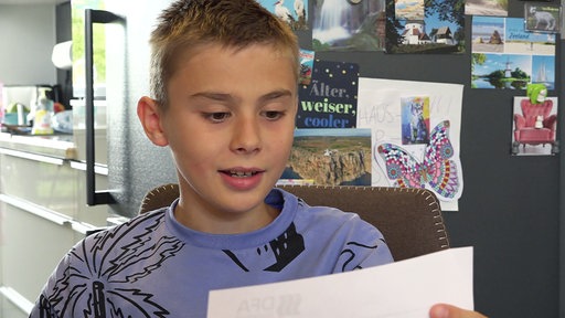 Felix hält den Antwortbrief auf seinen Ballon in der Hand.