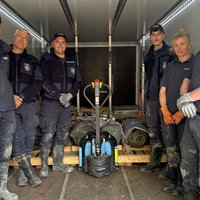 Mitarbeitende des Kampfmittelbeseitigungsdienstes stehen auf einer Ladefläche, auf der die entschärften Bomben liegen, und schauen in die Kamera.