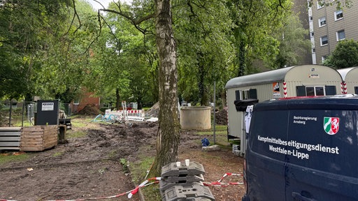 Zwischen mehreren Hochhäusern liegt die Fundstelle mehrerer Bomben. Im Vordegrund steht ein Auto des Kampfmittelbeseitigungsdienstes.