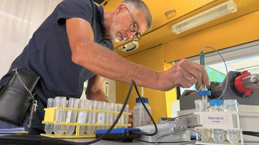 Heinz-Theo van Wickeren vom Verein VSR-Gewässerschutz führt in einem mobilen Labor eine Wasseruntersuchung durch.