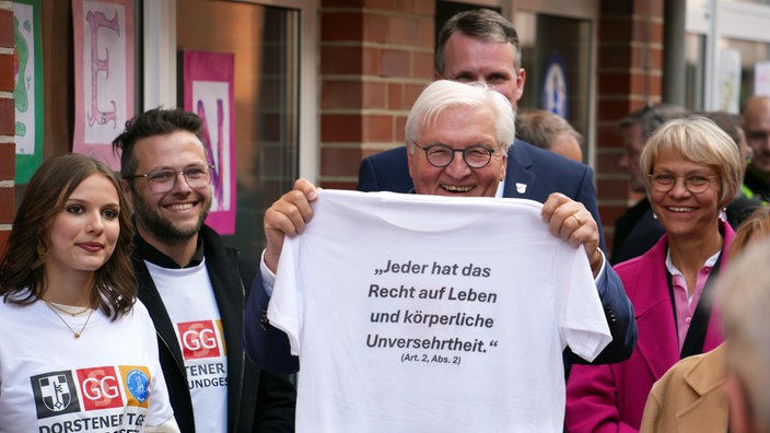 Frank-Walter Steinmeier hält ein T-Shirt hoch, mit der Aufschrift "Jeder hat das Recht auf Leben und körperliche Unversehrtheit."