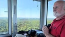 Ein Mann steht mit Fernglas in einem Wachturm