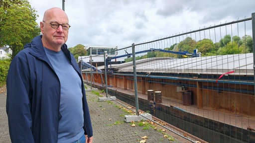 Älterer Mann steht lächelnd vor dem Frachtschiff