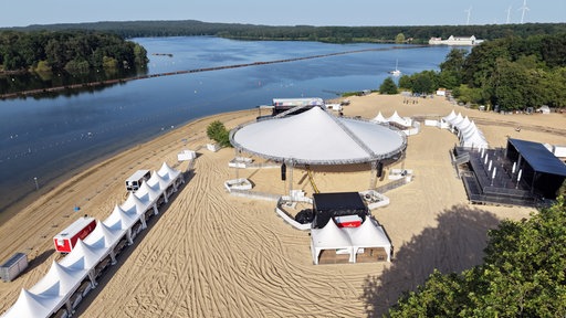 Zelte und Bühnen stehen auf dem gelben Strand direkt an der Wasserkante