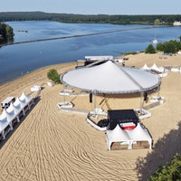 Zelte und Bühnen stehen auf dem gelben Strand direkt an der Wasserkante