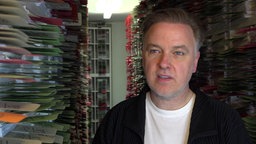 Anwalt Burkhard Benecken steht vor Regalen voller Akten