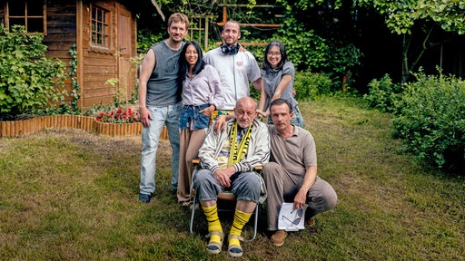 Eine Gruppe von unterschiedlich alten Menschen posieren für ein Foto im Garten.