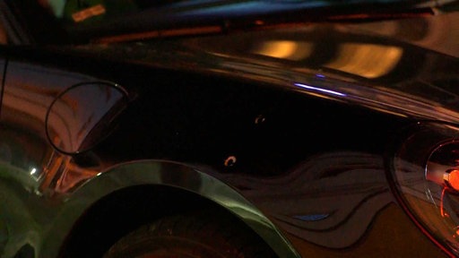 Neben der Tankklappe am vorderen Kotflügel des schwarzen Autos klaffen zwei Einschusslöcher.