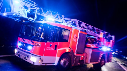 Ein Drehleiterwagen der Feuerwehr fährt mit Blaulicht vorbei.