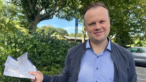 Benjamin Schmidt hält die gefälschten Konzertkarten in der Hand
