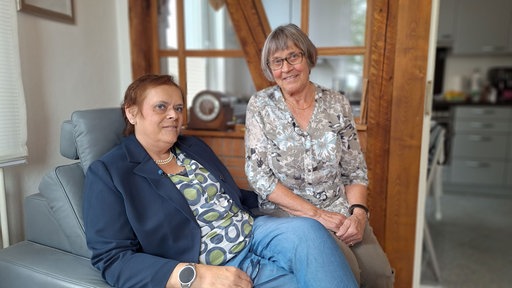 Porträt zweier Frauen: Kerstin Stolze sitzt auf einem Sessel. Neben ihr auf der Armlehne sitzt ihre Mutter Annette.