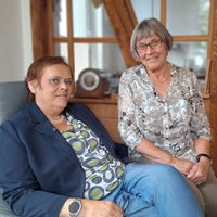 Porträt zweier Frauen: Kerstin Stolze sitzt auf einem Sessel. Neben ihr auf der Armlehne sitzt ihre Mutter Annette.