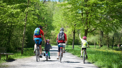 Eine Familie auf Fahrrädern fährt durch die Natur.