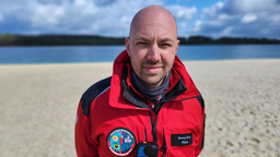 Ein Mann mit roter Jacke lächelt in die Kamera