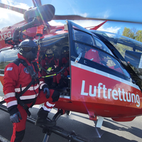 Ein Hubschrauberpilot steht vor einem roten Hubschrauber mit der Aufschrift Luftrettung