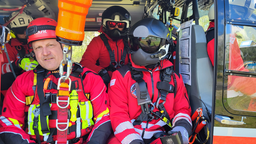 Ein Höhenretter der Dortmunder Feuerwehr hängt an einer Seilwinde, hinter ihm Männer mit Helmen