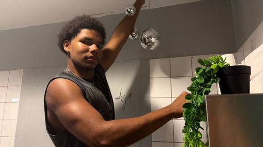 Ein Junge hängt eine Discokugel an die Decke