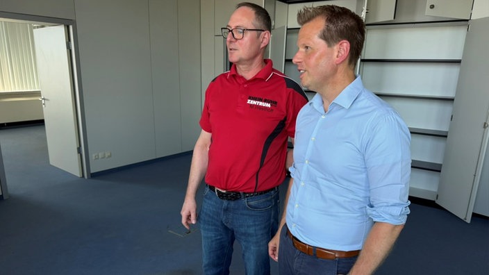 Geschäftsführer und Technikleiter stehen im Bürogebäude