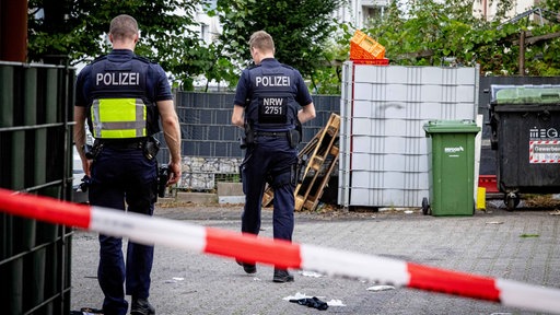 Zwei Polizisten hinter Absperrband. 