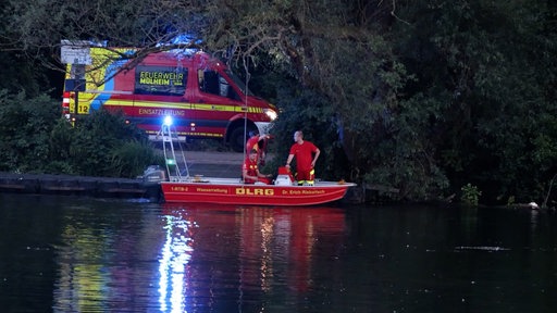 Ein Feuerwehrauto und ein Boot der DLRG am Ufer der Ruhr in Mülheim