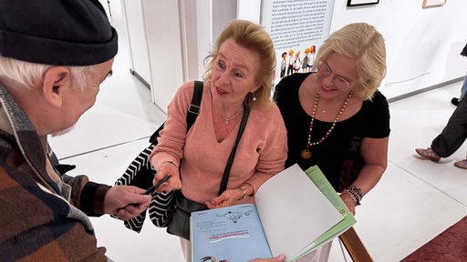 Hélène und Fredrika Wikland signieren ein Buch für ein Mann.