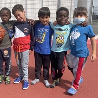 Amari steht zusammen mit fünf weiteren Freunden auf dem Fußballfeld im Friedensdorf Oberhausen.