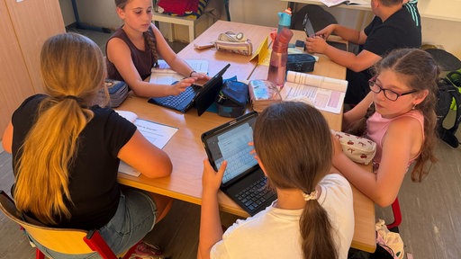 Kinder sitzen am Tisch in der Klasse