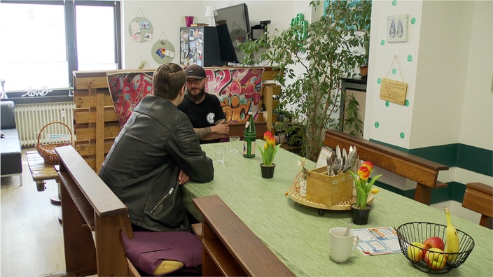 Zwei Männer sitzen an einem Tisch und unterhalten sich