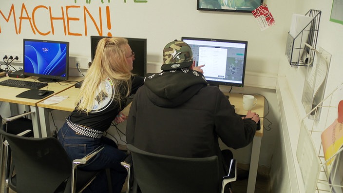 Eine Frau zeigt einem Mann etwas auf dem Computer