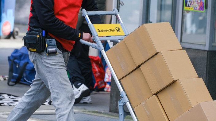 Ein Mann, der eine Sackkarre mit Paketen schiebt.