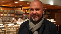 Inhaber Daniel Hein steht vor der Kuchentheke in seinem Café Strickmann in der Dortmunder Innenstadt