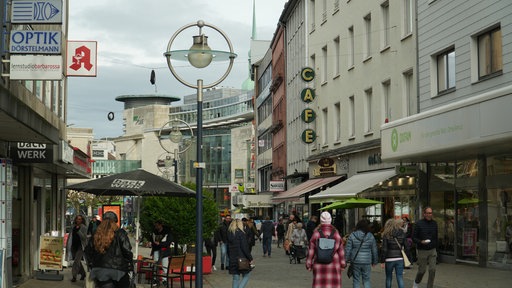 Passanten laufen in der Nähe vom Dortmunder Hansaplatz an Geschäften vorbei
