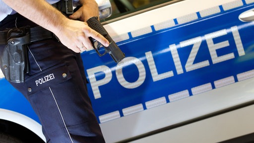 Ein Polizist hält seine Dienstwaffe vor sein Bein