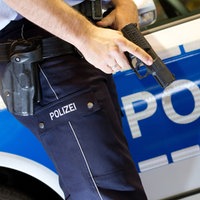 Ein Polizist hält seine Dienstwaffe vor sein Bein