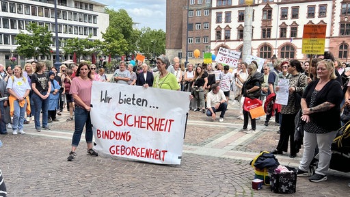 Mit einem weißen Plakat in der Mitte demonstrieren viele Tagesmütter vor dem Rathaus