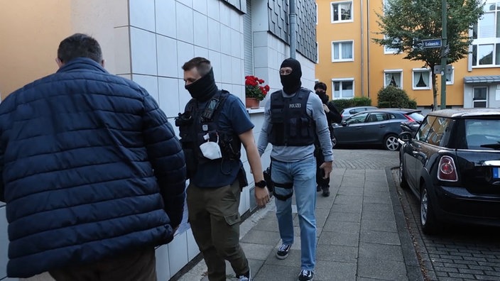 Maskierte Polizisten laufen in das Haus des Verdächtigen 