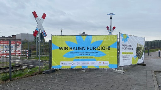 Ein großes, hellgünes Schild auf dem "Wir bauen für dich" steht