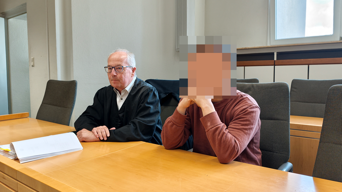 Der Angeklagte sitzt neben seinem Verteitiger im Gerichtssaal.